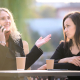 Two womeon at a table, one distracted on teh phone, other waiting to talk. Get and Hold a person's attention article
