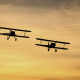flying under the radar - image of two biplanes flying low at sunset